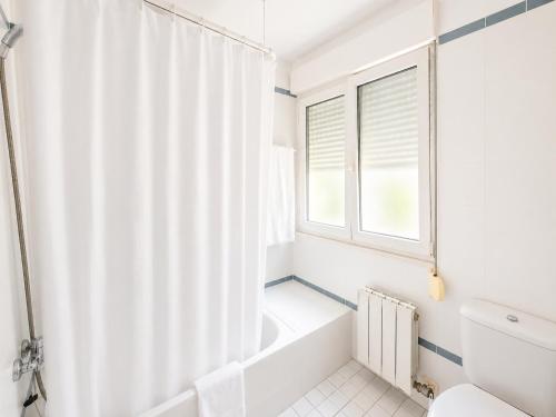 a bathroom with a tub and a toilet and a window at Hostal ** EC León in León