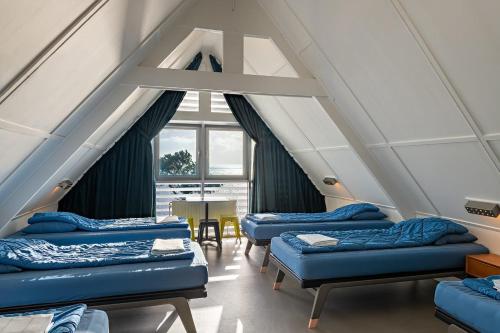 a room with four beds and a window at Stayokay Hostel Terschelling in West-Terschelling