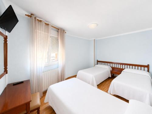 a hotel room with two beds and a television at Hostal ** EC León in León