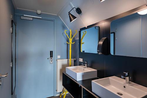 a bathroom with two sinks and a large mirror at Stayokay Hostel Terschelling in West-Terschelling