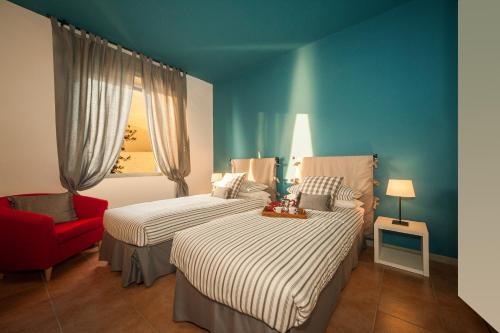 een slaapkamer met 2 bedden en een rode stoel bij Casa Dante in Sale Marasino