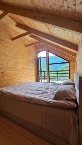 a large bed in a wooden room with a window at Cozy Cottage Wild Freedom in Didi Ateni