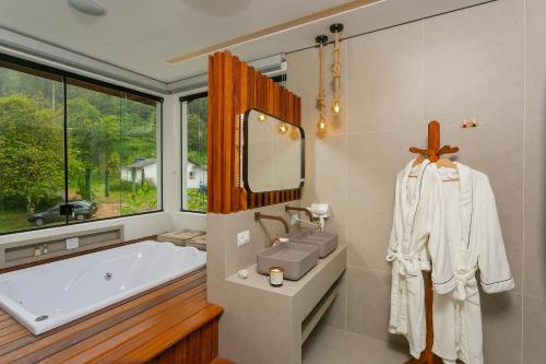 a bathroom with a tub and a sink and a mirror at Pousada Paraíso Almada in Ubatuba