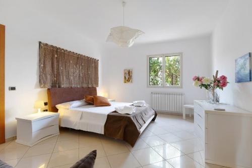 a bedroom with a bed and a table and a window at Appartamento Venere in villa 15pax in Marina di Ragusa
