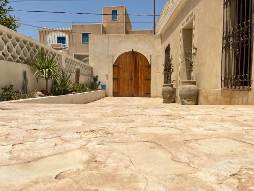 a house with a wooden door and a patio at Dar Younes in Houmt Souk