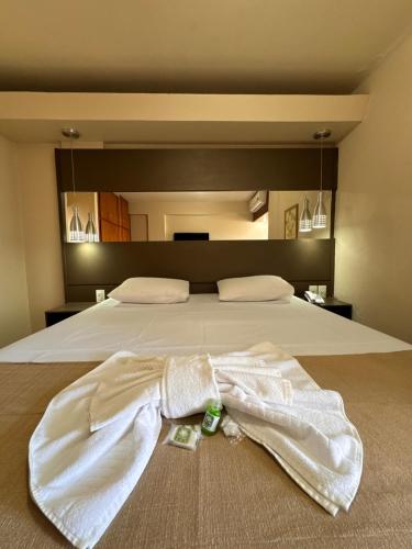 a white robe laying on top of a bed at Hotel Veredas in Paracatu