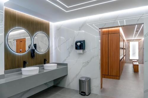 ein Badezimmer mit zwei Waschbecken und zwei Spiegeln in der Unterkunft Radisson Blu Hotel, Kuwait in Kuwait