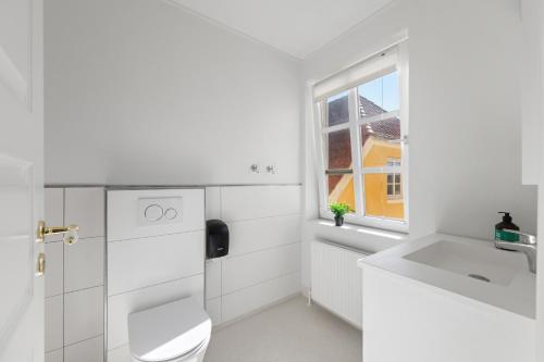 a white bathroom with a toilet and a sink at Løkken Badehotel Apartments in Løkken