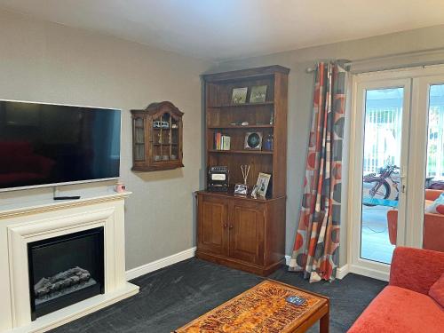 a living room with a fireplace and a flat screen tv at Pinecote in Bottesford