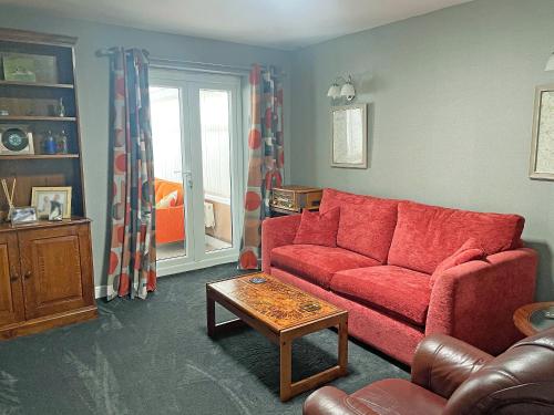 a living room with a red couch and a table at Pinecote in Bottesford