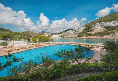 a swimming pool with a view of a body of water at Palladium Hotel Cala Llonga - Adults Only in Cala Llonga