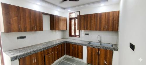 a kitchen with wooden cabinets and a sink at Hotel Aroha Stayz At Sector 44 Noida in Noida