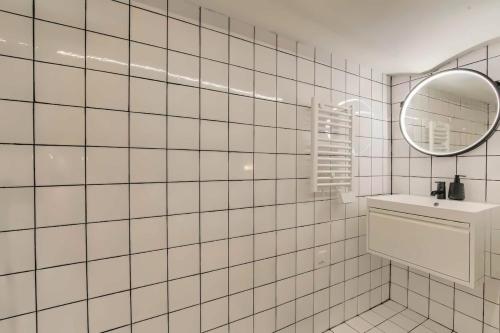 a white tiled bathroom with a sink and a mirror at Lyon Cité Internationale - Loft Industriel Neuf in Caluire-et-Cuire