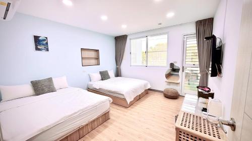 a small room with two beds and a tv at 小邱民宿 in Anping