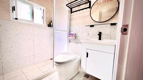 a bathroom with a toilet and a sink and a mirror at 小邱民宿 in Anping