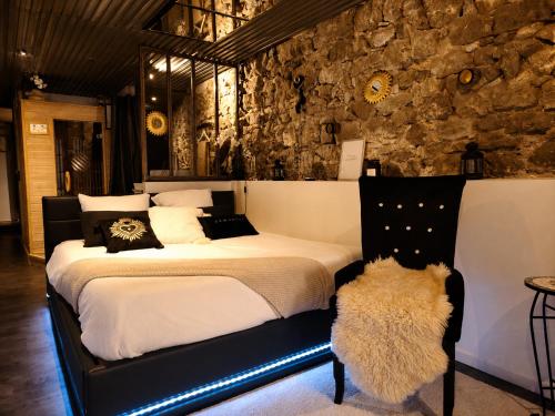 a bedroom with two beds and a stone wall at Sweet Loft Grenoble-Love Room avec jacuzzi & sauna in Grenoble