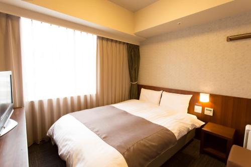 a hotel room with a bed and a window at Dormy Inn Kumamoto Natural Hot Spring in Kumamoto
