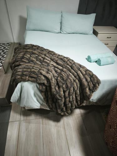 a bed with a brown blanket on top of it at Maphango Farms BnB in Alice