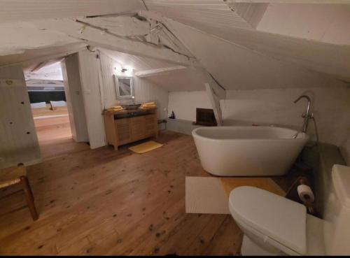 a bathroom with a white tub in a attic at La Maison d'ART in Lacour