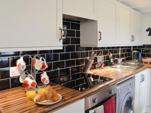 a kitchen with white cabinets and a wooden counter top at Wee Dug Hoose in Glenluce