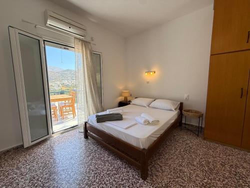 a bedroom with a bed and a large window at Nion Stays in Katapola