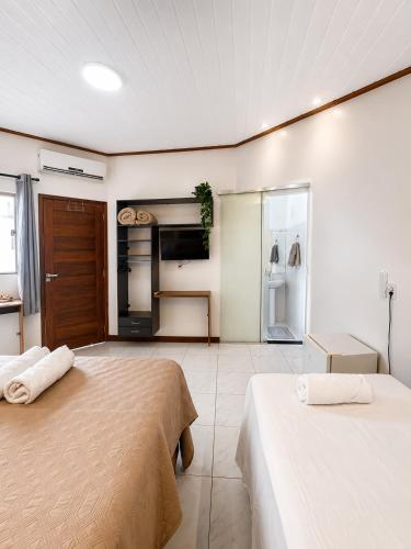 two beds in a large room with a kitchen at Pousada Alter Villa Suítes in Alter do Chao