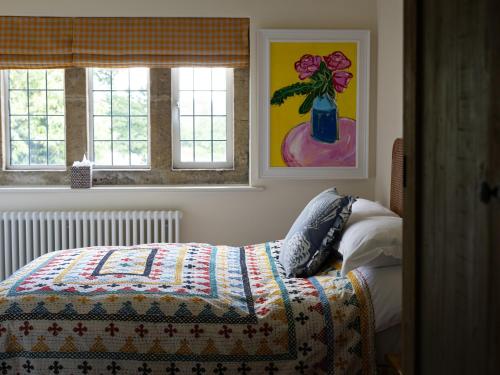 a bedroom with a bed with a colorful quilt and two windows at Costers Lodge in Midhurst