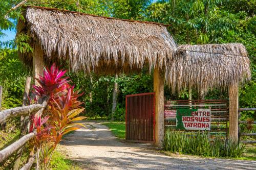 a hut with a straw roof and a sign at Entre Bosques Tayrona in Los Naranjos