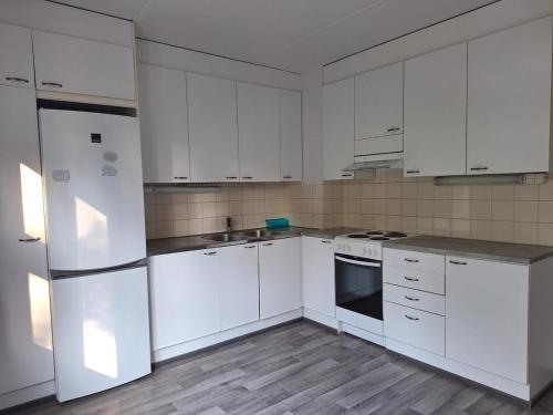 a white kitchen with white appliances and white cabinets at Private bedroom in Shared Apartment in Hämeenlinna