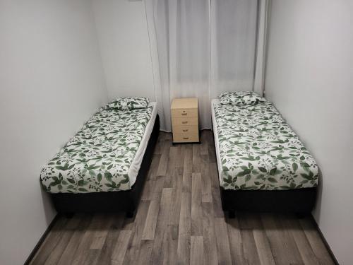two beds in a room with a wooden floor at Private bedroom in Shared Apartment in Hämeenlinna