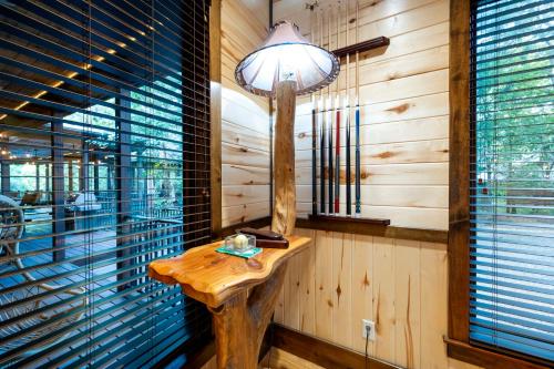 a table in a room with a lamp and windows at Call It A Day Luxury Cabin in Stephens Gap