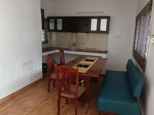 a kitchen with a wooden table and a blue chair at Gurudeva stay inn in Covelong