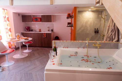 a bathroom with a tub with a shower and a table at La Seventies'room in Dijon