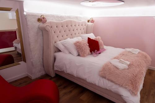 a bedroom with a white bed with pink pillows at La Seventies'room in Dijon