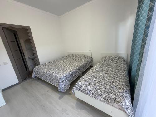 two beds in a small room with a door at Atabek in Bosteri