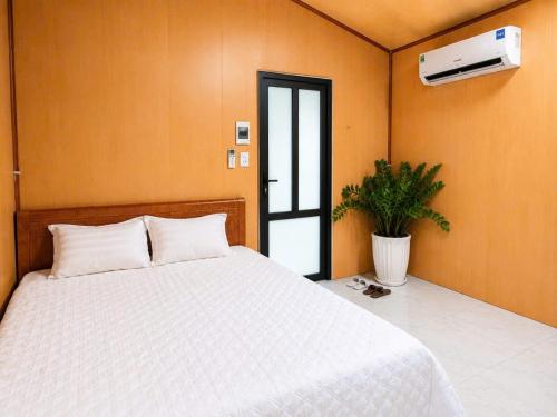 a bedroom with a white bed and a plant at Haven Kitchen & Cafe in Nguyễn Thôn