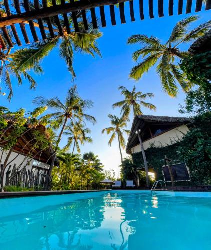 a swimming pool in front of a resort with palm trees at Serena Pousada - Icaraí de Amontada in Icaraí