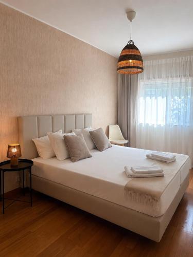 a bedroom with a large white bed with a pendant light at Casa do Pirata by GuestPro in Matosinhos