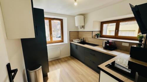 a kitchen with black and white cabinets and a window at Le Tertre du Loing - Forêt de Fontainebleau - Gare in Montigny-sur-Loing