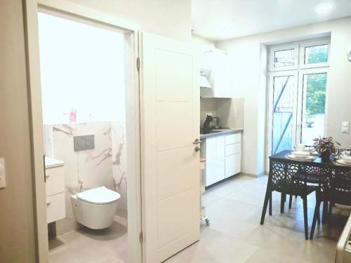 a white bathroom with a toilet and a table at Chez Alice 2 in Montbéliard