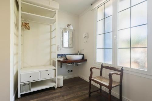 a bathroom with a sink and a chair and a window at MR Hotelet de la Raconà & Apartments in Denia