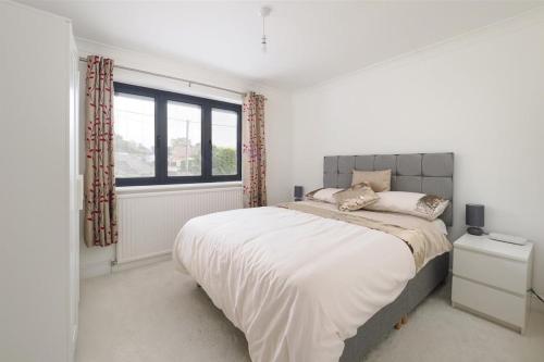 a white bedroom with a large bed and a window at Architectural Gem with Luxury Outdoor Kitchen in Chilham