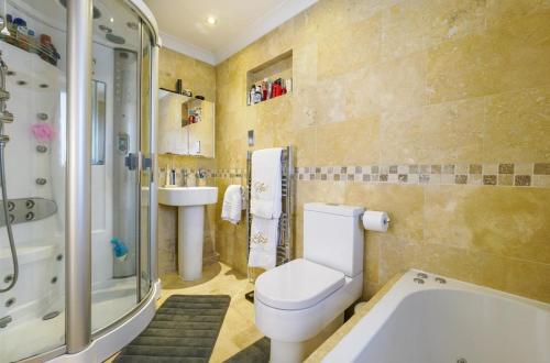 a bathroom with a toilet and a sink and a tub at Architectural Gem with Luxury Outdoor Kitchen in Chilham
