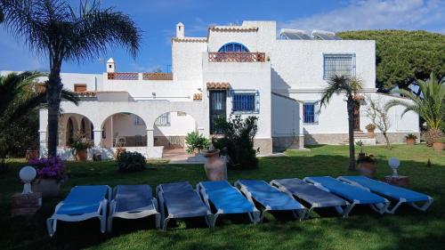 a group of blue chairs in front of a house at Finca Malyma with 2 villas and 1 apartment, beach front 10,000m2 botanic garden in Zahora