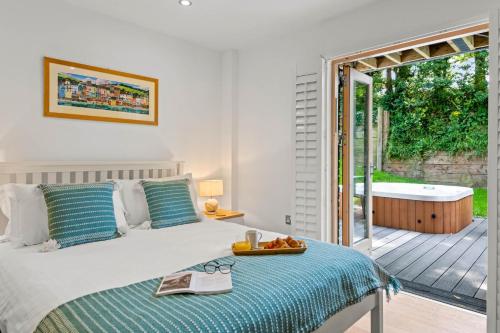 a bedroom with a bed and a tub and a balcony at House 29 in Looe
