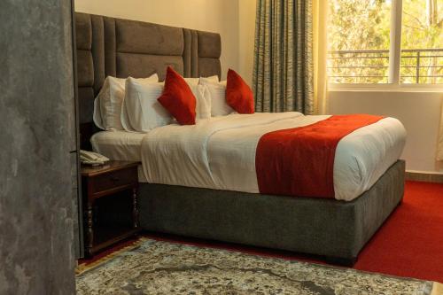 a bedroom with a large bed with red pillows at GRANADA HOTEL NAIROBi in Nairobi