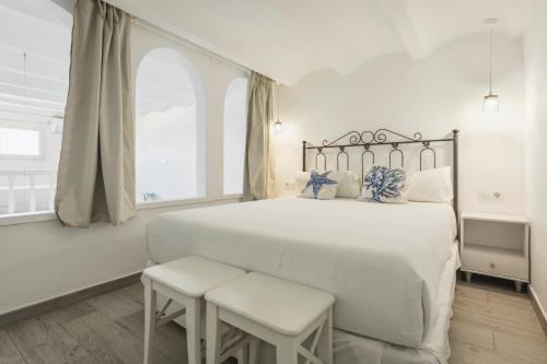 a white bedroom with a large bed and a window at MR Hotelet de la Raconà & Apartments in Denia