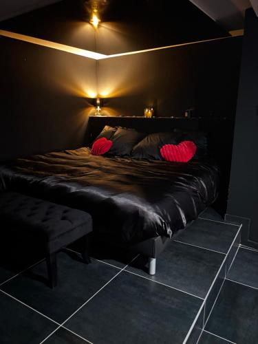 a black bed with red pillows in a dark room at House-Evasion in Tuchan