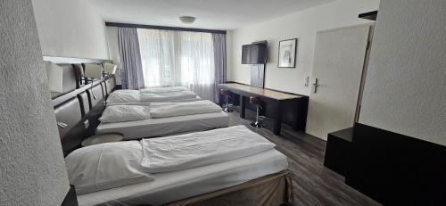 a hotel room with three beds and a television at Apartment Hotel Citylight in Cologne