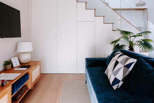 a living room with a blue couch and a staircase at The Charming Loft in Esposende